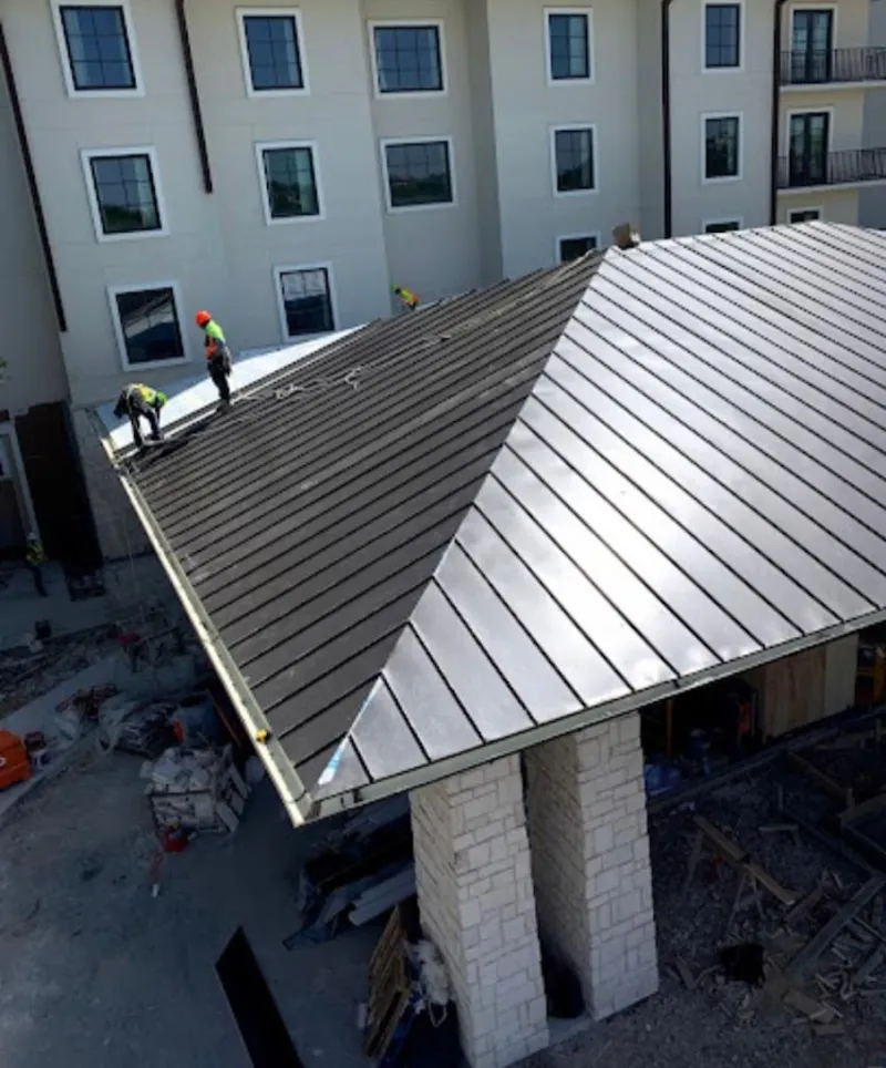 Crew installing standing seam metal roof panels on a commercial project in Lemont